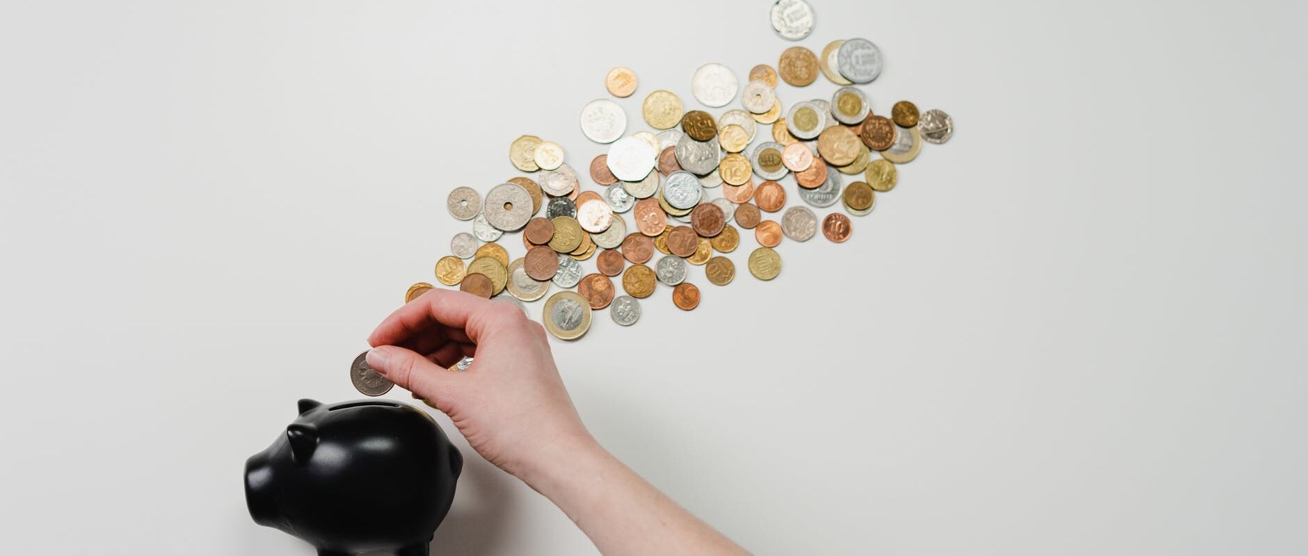 person putting coin in a piggy bank