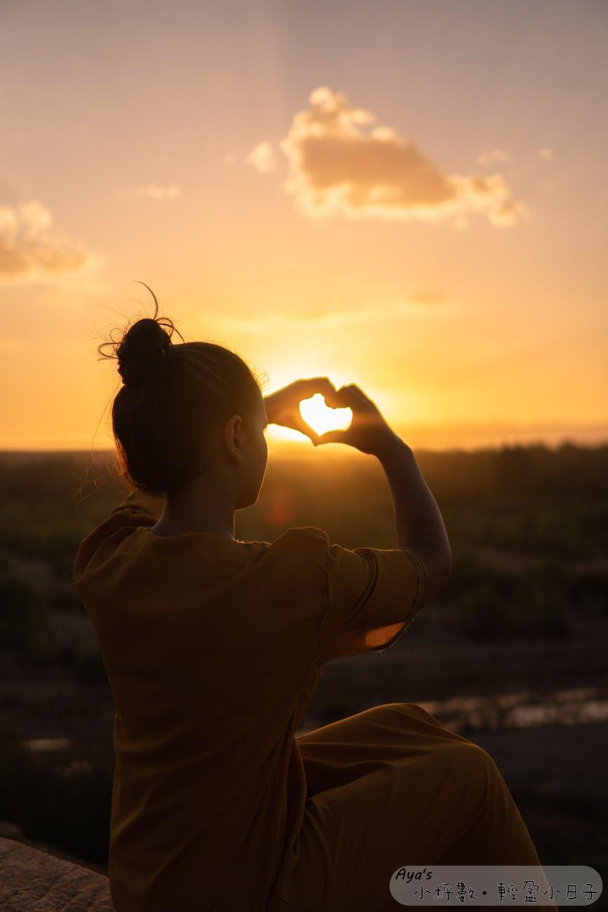 woman sitting while showing heart sign hands